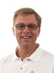 Leende man i vit tröja och glasögon.