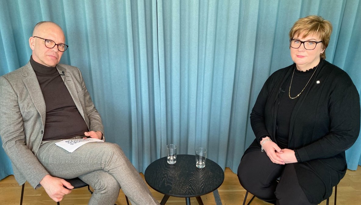 En man och en kvinna sitter ner och tittar in i kameran.