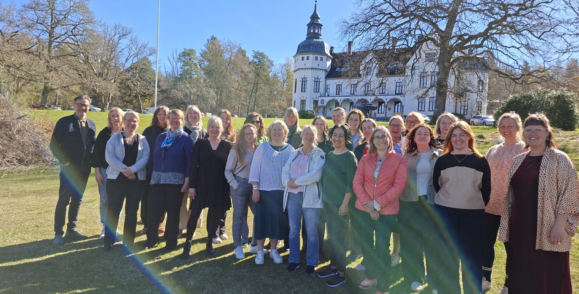 En grupp människor utomhus i solsken och blå himmel.