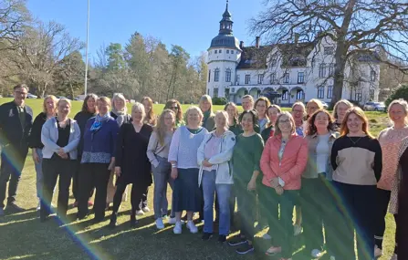 En grupp människor utomhus i solsken och blå himmel.