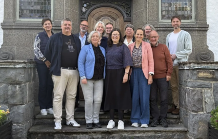 En grupp människor utomhus på en trappa framför en skolbyggnad.