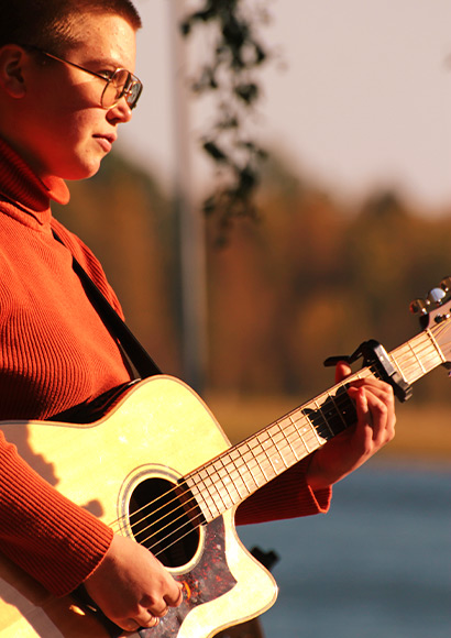 Bild: Deltagare p&aring; Singer/Songwriter spelar gitarr utomhus.