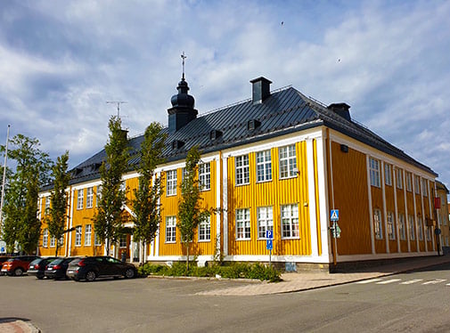 Bild: Sverigefinska folkh&ouml;gskolan, en gul tr&auml;byggnad vid torget i Haparanda.